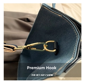 Detail shot of golden metal swivel hook and stitching on blue denim tote bag