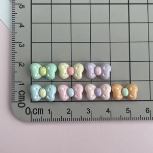 Mini resin bow charms for DIY crafts showing 1cm size measurement on a ruler