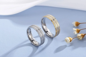 Detail of matte brushed titanium steel couple rings in silver and gold tone finish