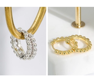 Macro detail of S925 sterling silver beaded hoop earrings in gold and silver finishes