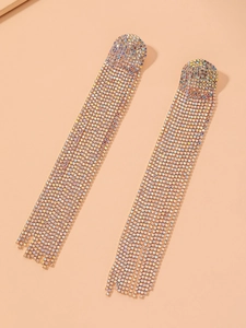 Détail de boucles d'oreilles à pompons en strass colorés sur fond rose doux