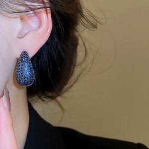 Detail view of dark blue teardrop earrings with pavé zircons on a model's ear