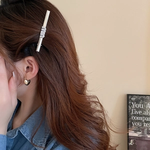 Detailed view of silver Y2K hair clip with rhinestone letters and golden heart ear cuff