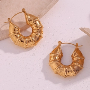 Detailed macro shot of chunky 18K gold hollow tire textured hoops on water droplet surface