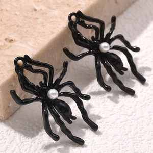 Detailed macro view of black spider charms with a white pearl accent for DIY jewelry