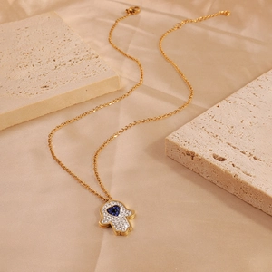 Hamsa Hand necklace in gold with white rhinestones and a blue heart gemstone center