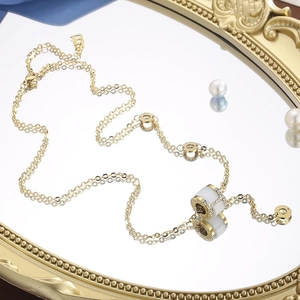 Detail view of gold double chain necklace with cat eye cylinder pendant and small crystals