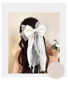 Detail of oversized cream white mesh bow hair clip with flowing ribbons on model back head