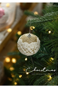 Detail of 8cm gold glitter Christmas ball with white lace hanging on a tree