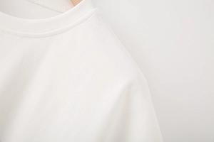 Détail du t-shirt blanc à col rond avec coutures côtelées et texture en coton