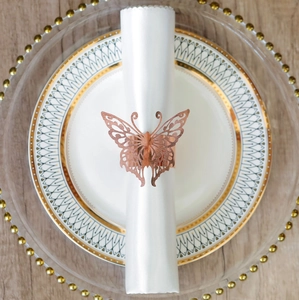 Detailed view of rose gold cutout butterfly metal napkin ring on a white linen napkin
