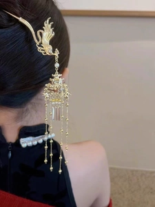 Détail d'un pic à cheveux phénix doré avec de longs glands et perles sur fond noir