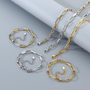 Close-up of gold and silver twisted cable chain necklaces and bracelets on grey podium
