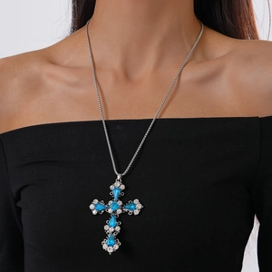 Detail of cross pendant necklace with blue crystals and white rhinestones on model