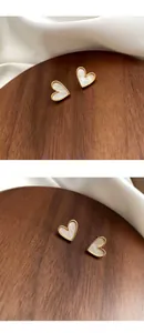 Macro detail of heart-shaped gold stud earring featuring natural white mother-of-pearl inlay