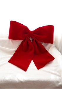 Detailed texture of a large red velvet Christmas bow on a soft white plush background