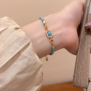 Detailed view of turquoise beaded bracelet with pearls and gold floral metal accents