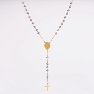 Détail du collier rosaire doré avec perles violettes et pendentifs croix et médaille