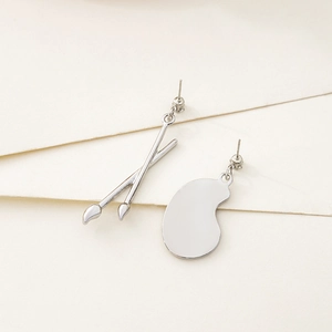 Detailed view of silver asymmetric artistic earrings featuring paintbrush and palette