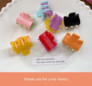 Close-up of mini candy-colored plastic claw clips in assorted bright colors on a white plate