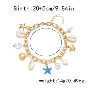 Detail of bohemian gold bracelet with white shells, blue starfish, and pearls on white background