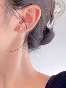 Close-up of minimalist S925 silver pearl flower studs and small ball earrings on ear