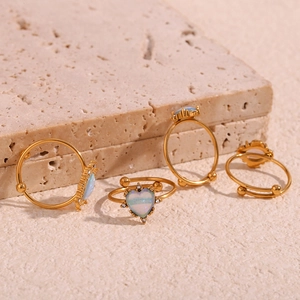 Detail of 18K gold plated adjustable rings with opal stones and crystals on a stone surface