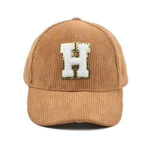 Detail einer braunen Cord-Baseballkappe mit glitzerndem H-Buchstaben-Patch und Textur