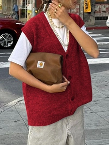 Dettaglio del gilet in maglia rossa con scollo a V e bottoni in ambiente urbano