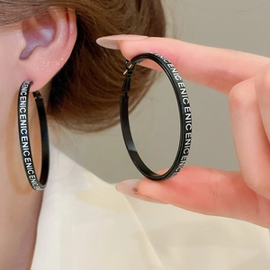 Détail de grandes créoles noires avec inscription ENICE blanche sur un mannequin