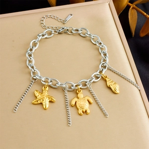Macro shot of silver stainless steel chain with gold starfish, turtle and shell charms