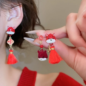 Close-up of festive red zodiac earrings with gold Fu character and silk tassels