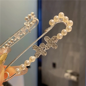 Detail of silver safety pin with pearls and rhinestone crosses for waist adjustment