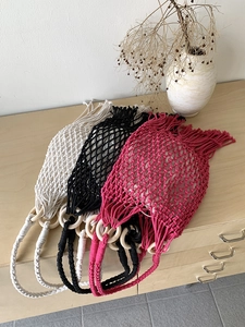 Detail of woven macrame bags with round wooden handles in white black and rose colors