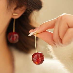 Detail of cherry resin earrings with subtle glitter and elegant gold stems worn by model