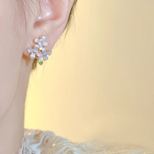 Chic purple floral stud earrings with enamel petals and gold base worn by a model