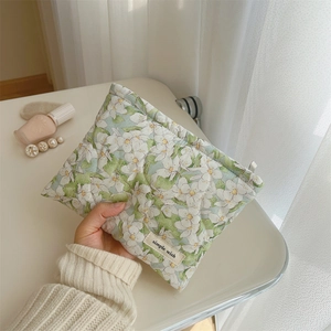 Quilted floral makeup pouch in light green fabric held by a model for storage