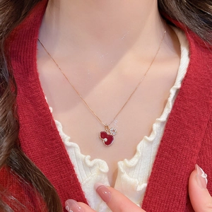 Detailed view of a gold gourd necklace with red enamel and coin charms on a model