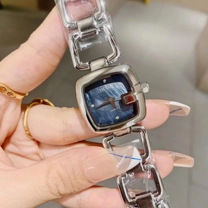 Detailed close-up of a silver square watch with a blue textured dial and gold markers