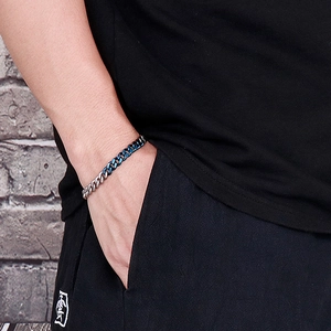 Detail of two-tone silver and blue stainless steel Cuban link bracelet on wrist