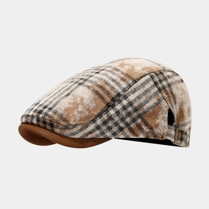 Detail view of plaid newsboy cap with brown suede brim and adjustable metal buckle closure