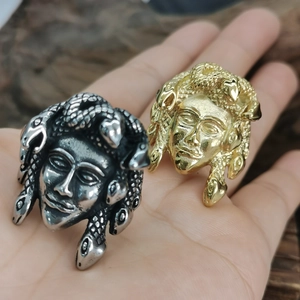 Detailed relief of golden and silver Medusa head rings on a textured wooden background