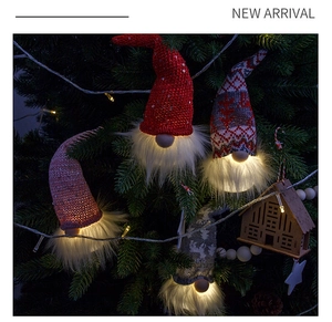 Close-up of glowing Christmas forest gnome pendants with warm lights on a green tree