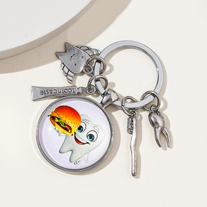 Detailed macro view of dental themed silver keychain with winged tooth and toothbrush pendants