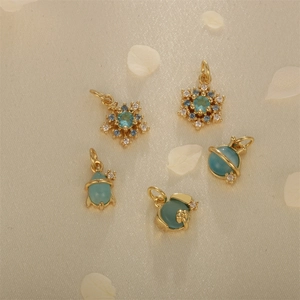 Detailed close-up of five gold-plated pendants with blue stones on beige silk fabric