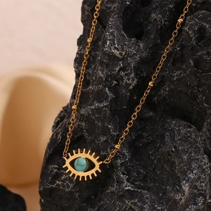 Macro shot of 18K gold plated evil eye necklace with turquoise stone on dark rock
