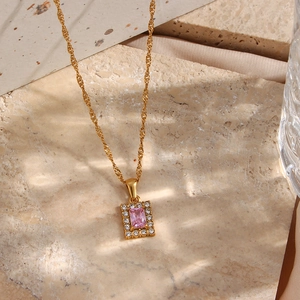 Macro view of gold water wave chain with rectangle pink zircon pendant on satin