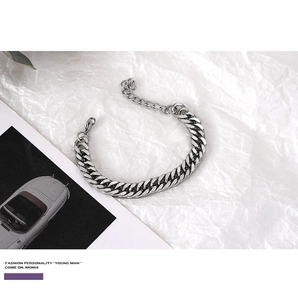 Detailed close-up of a silver Cuban link bracelet with lobster clasp on a stylish background