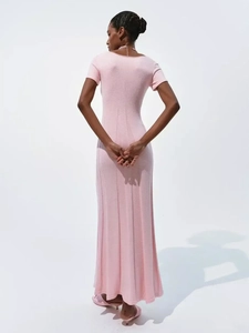 Detail of a pink knitted maxi dress showing back view and slim fit silhouette on model
