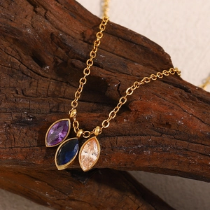 Detail shot of 18K gold plated necklace with three colorful marquise zircons on wood